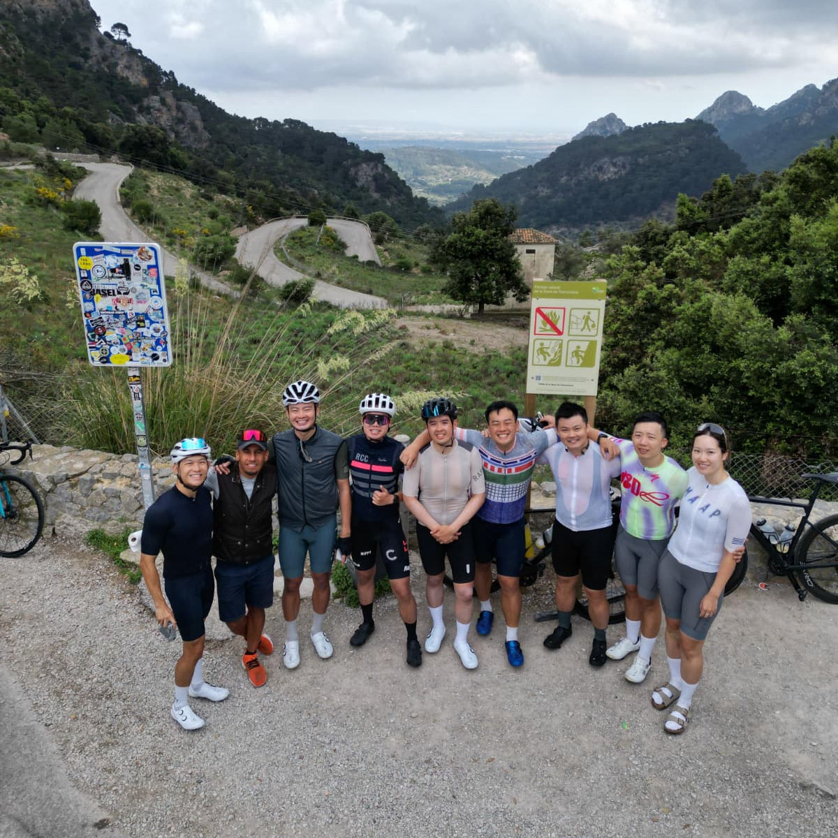 Group of cyclists posing for a photo on a mountain road with scenic views.